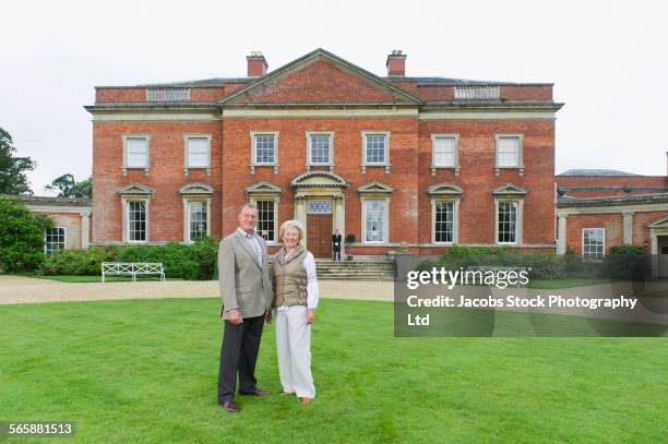 caucasian couple smiling outside mansion - stately home stock pictures, royalty-free photos & images