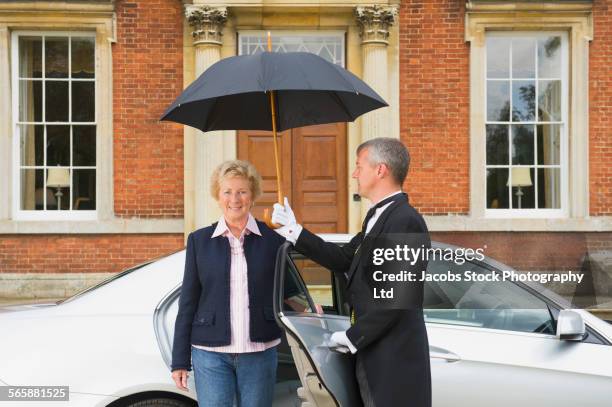 caucasian butler holding umbrella outside car door for woman - car profile stock pictures, royalty-free photos & images