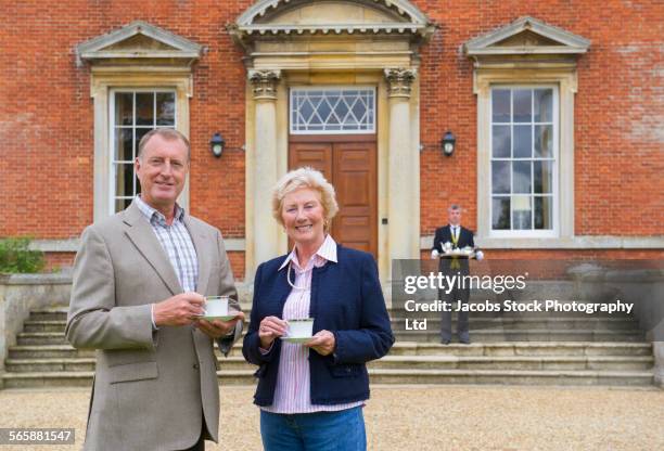 caucasian couple drinking tea outside mansion with butler - northants stock pictures, royalty-free photos & images