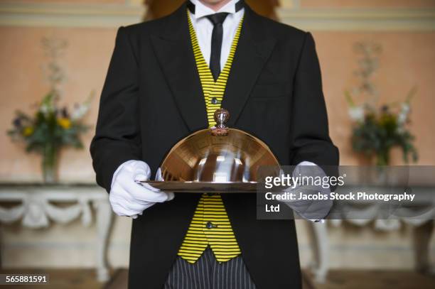 caucasian butler holding serving tray in formal parlor - maggiordomo foto e immagini stock