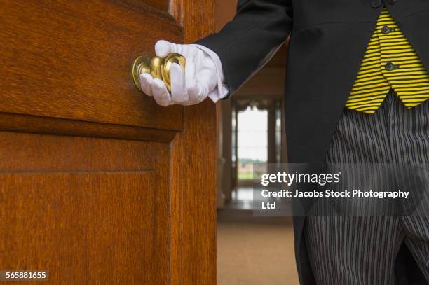 close up of caucasian butler opening door - hotel uniform stock-fotos und bilder