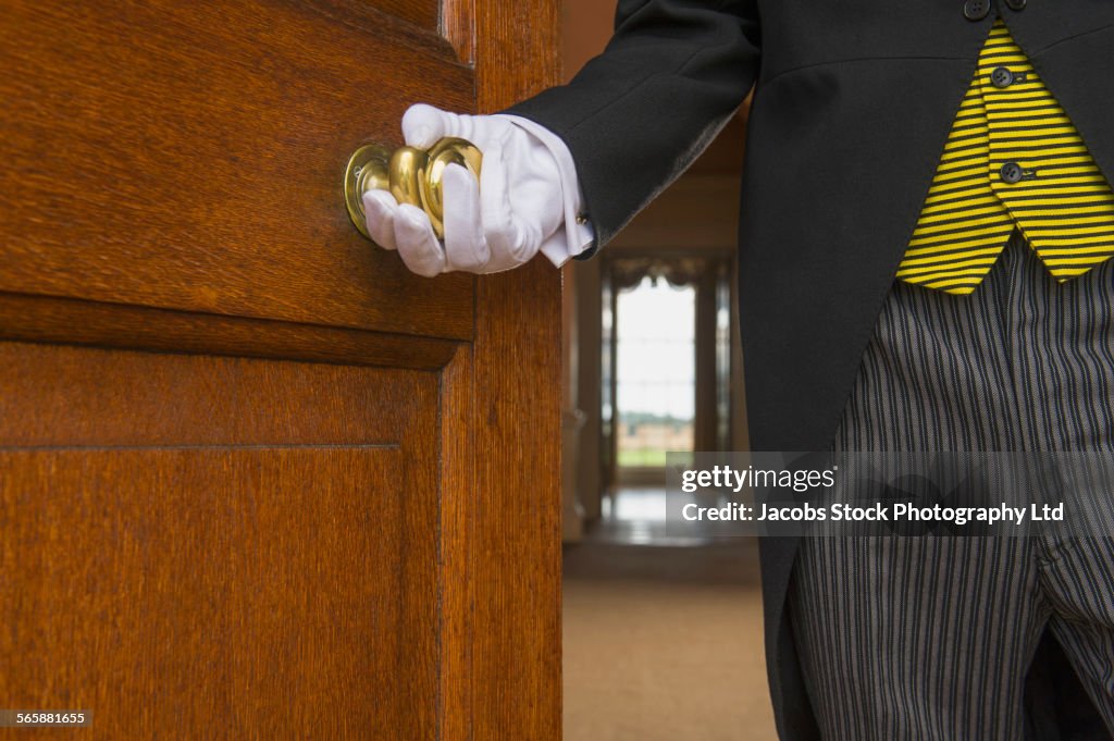 Close up of Caucasian butler opening door