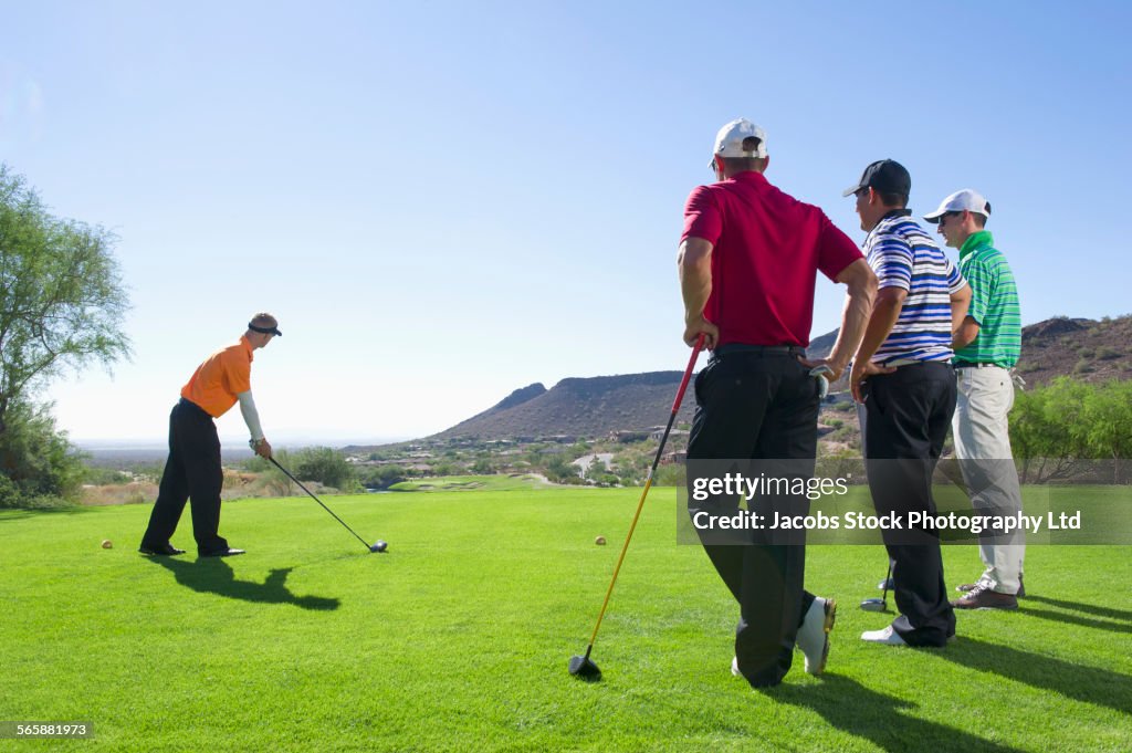 Men playing golf on course