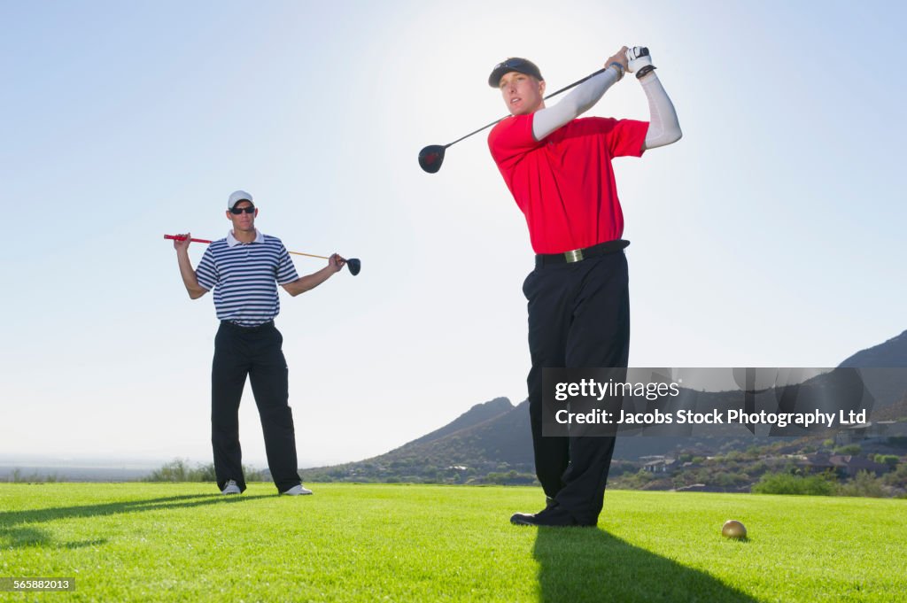 Caucasian men playing golf on course