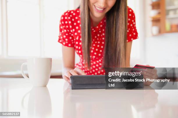 mixed race woman shopping online in kitchen - red billed stock pictures, royalty-free photos & images