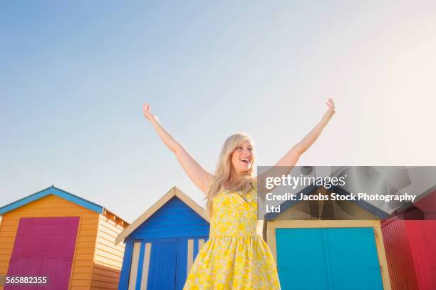 caucasian woman cheering near colorful beach huts - multi colored dress bildbanksfoton och bilder