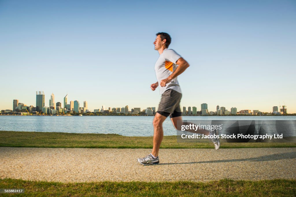 Caucasian man running near urban waterfront, Perth, Western Australia, Australia
