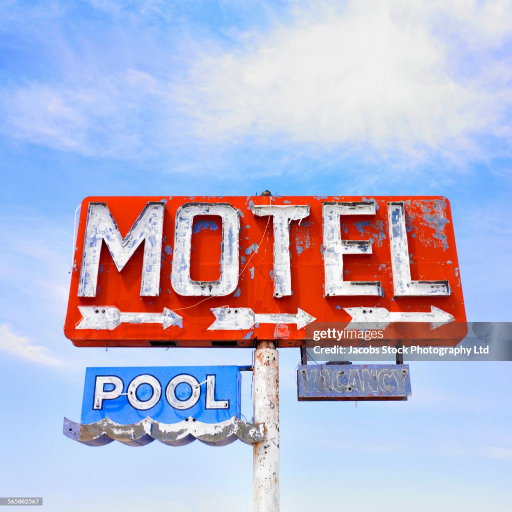 Dilapidated motel neon sign under blue sky