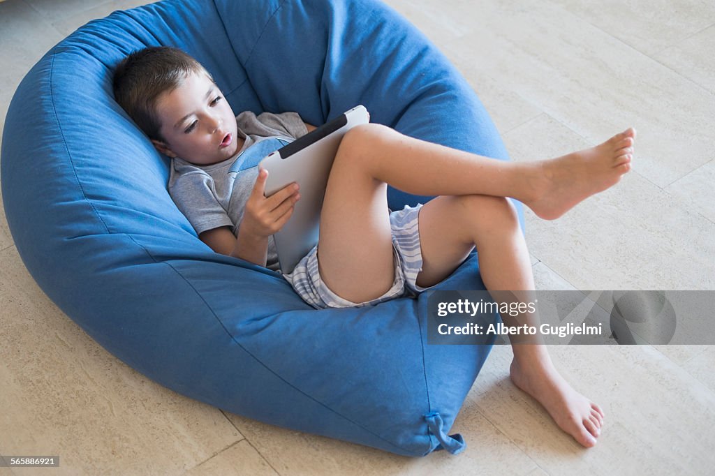 Caucasian boy using digital tablet in beanbag chair