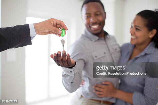 real estate agent giving couple keys to new home - home ownership keys stock pictures, royalty-free photos & images