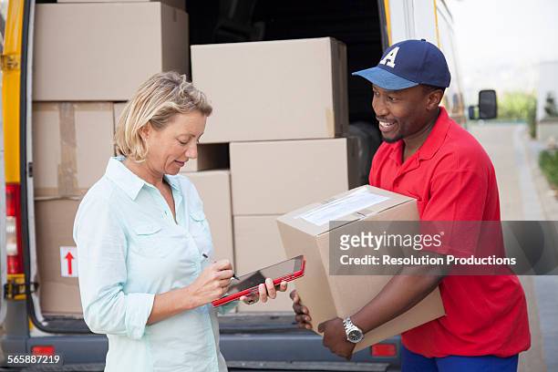 delivery man holding cardboard box with customer - signature collection stock-fotos und bilder