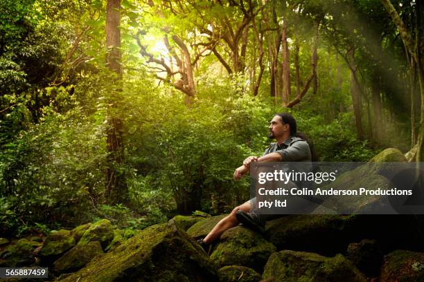 hawaiian hiker sitting on boulder in forest - honolulu culture stock pictures, royalty-free photos & images