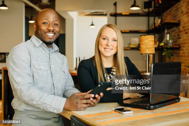 waiter and businesswoman using technology in cafe - african american restaurant texting stockfoto's en -beelden