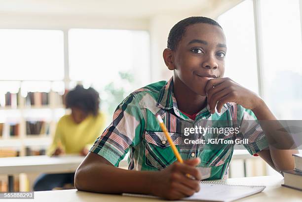 black student thinking in classroom - boy thinking stock-fotos und bilder