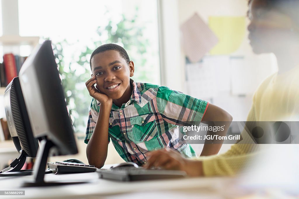 Black student smiling near computers in classroom