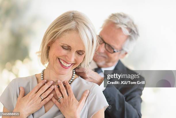 smiling older caucasian man giving wife a necklace - couple jewelry stockfoto's en -beelden