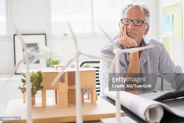 older caucasian architect examining scale model in office - retirement plan imagens e fotografias de stock
