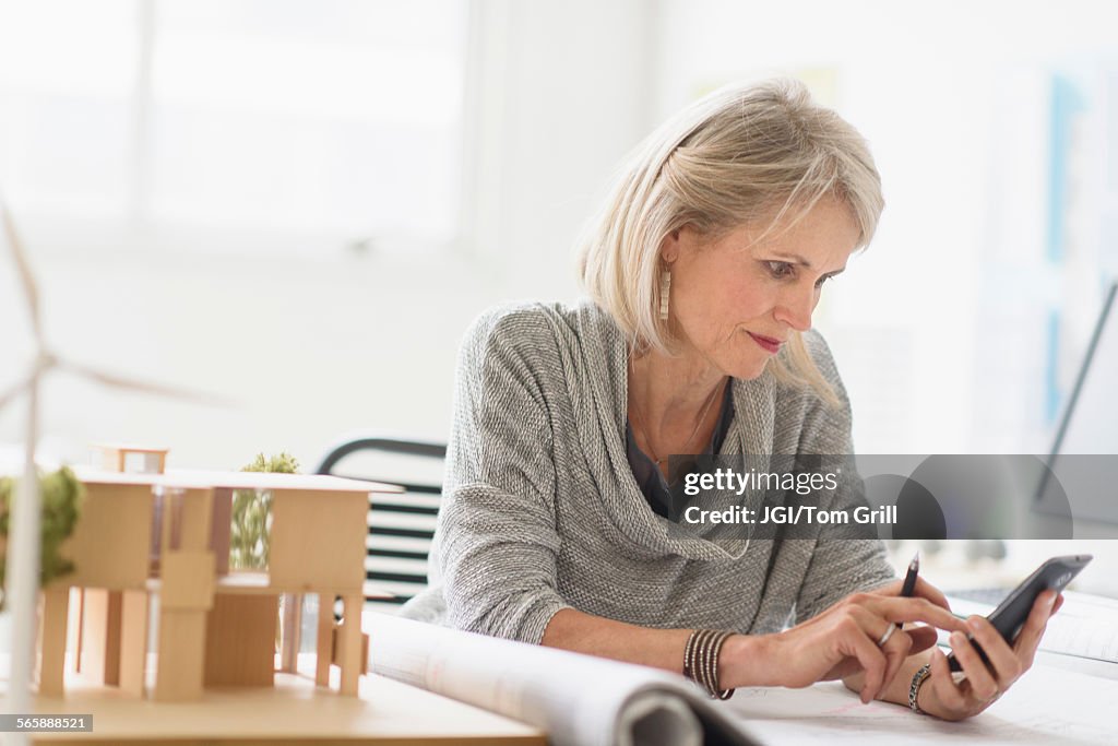 Older Caucasian architect using cell phone in office