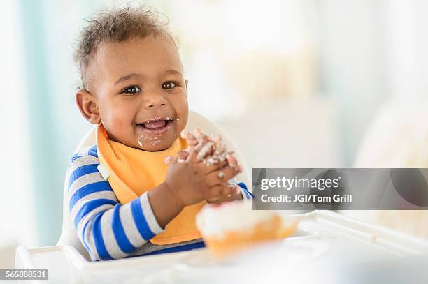 mixed race baby boy eating in high chair - よだれ掛け ストックフォトと画像