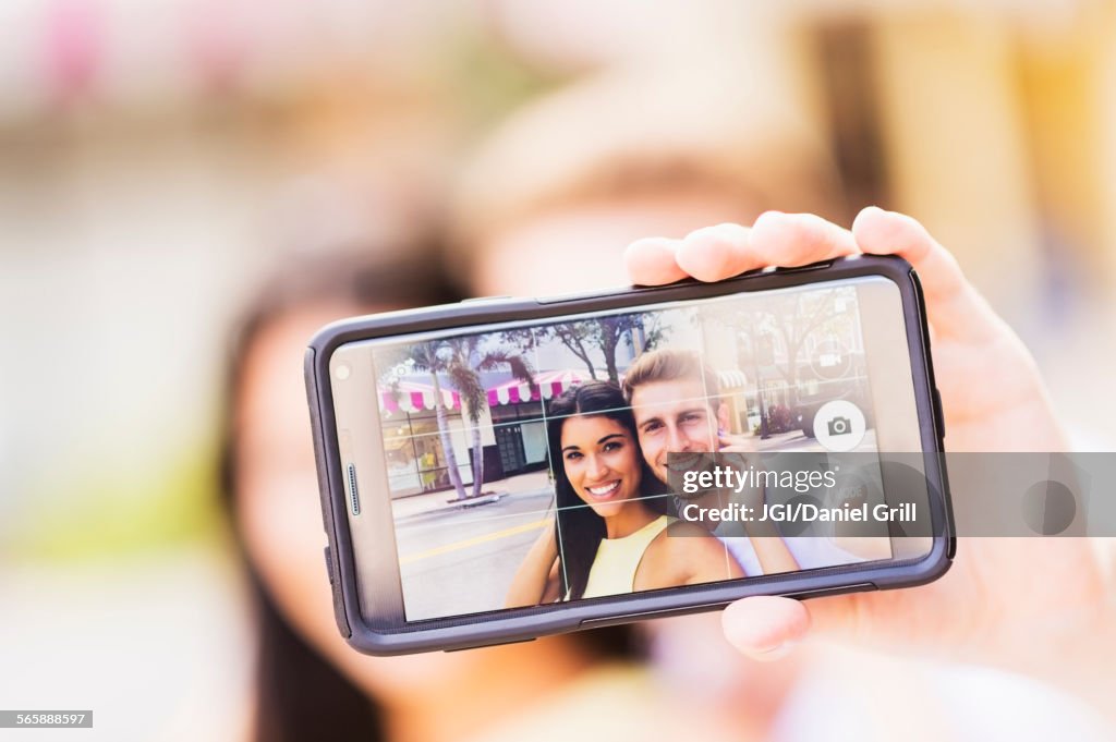 Close up of Hispanic couple taking selfie outdoors