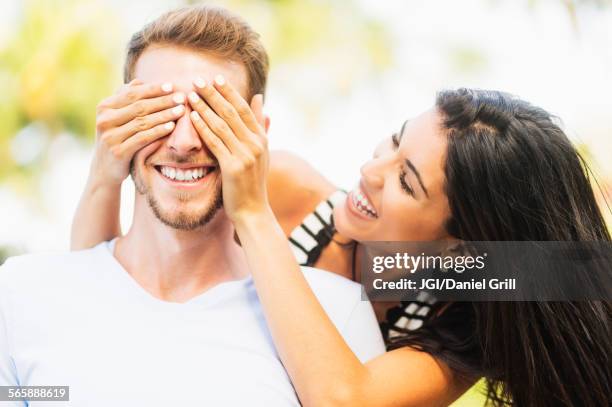 hispanic woman covering eyes of boyfriend outdoors - romance cover stock pictures, royalty-free photos & images