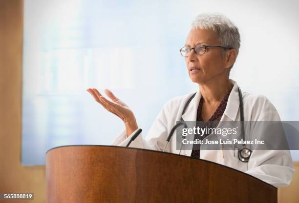 mixed race doctor speaking at podium - lectern stock pictures, royalty-free photos & images