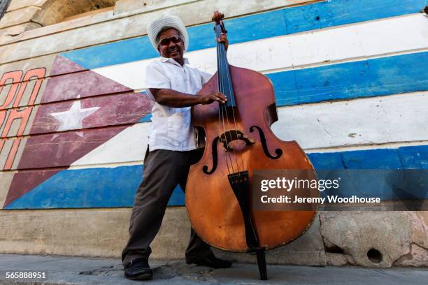 hispanic musician playing upright bass near cuban flag, santiago de cuba, santiago, cuba - santiago de cuba photos et images de collection