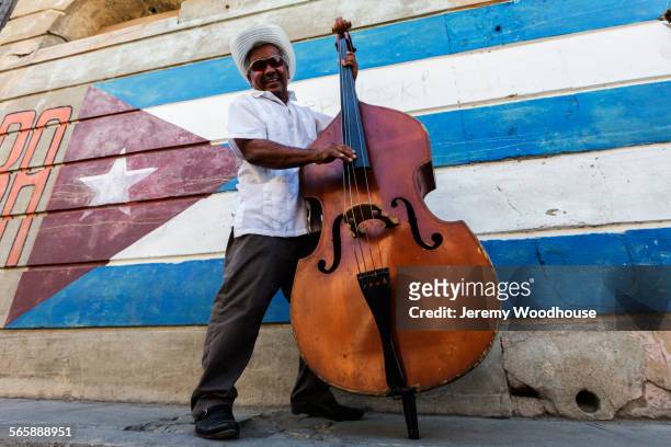 hispanic musician playing upright bass near cuban flag, santiago de cuba, santiago, cuba - double bass stock pictures, royalty-free photos & images