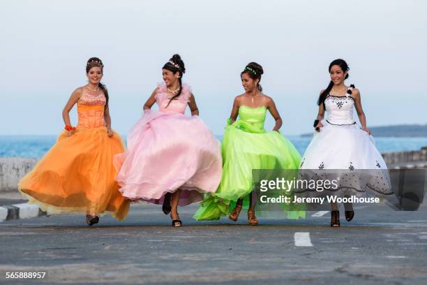 Hispanic teenage girls running in ball gowns