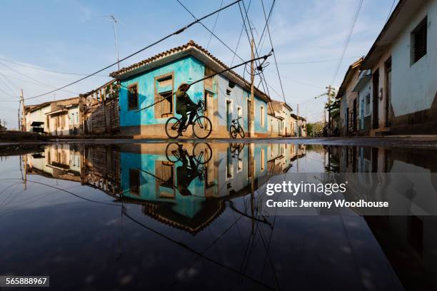 man on bicycle and buildings reflecting in puddle, remedios, santa clara, cuba - santa clara cuba stock pictures, royalty-free photos & images