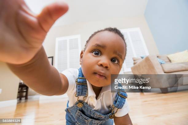 black baby reaching for camera on living room floor - black baby 個照片及圖片檔