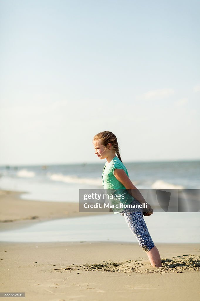 Caucasian girl leaning in sand on beach