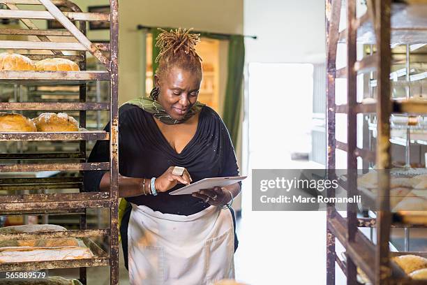 black baker using digital tablet in bakery kitchen - email list stock pictures, royalty-free photos & images