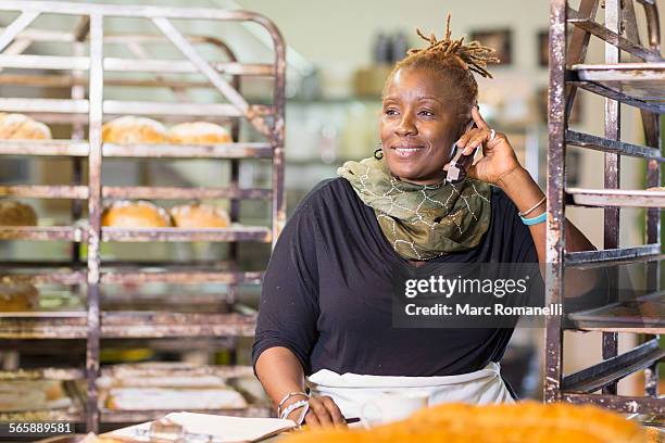 black baker talking on cell phone in bakery kitchen - black business owner ストックフォトと画像