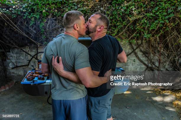 gay couple kissing and grilling food in backyard - couple grilling stock-fotos und bilder