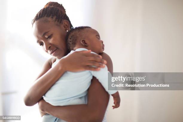 black mother holding sleeping baby - black man holding baby stock-fotos und bilder