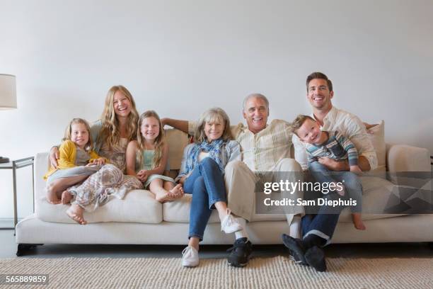 caucasian multi-generation family sitting on sofa in living room - grandmas living room stockfoto's en -beelden