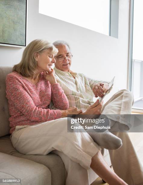 older caucasian couple using digital tablet on sofa - wellness kindness love stock pictures, royalty-free photos & images