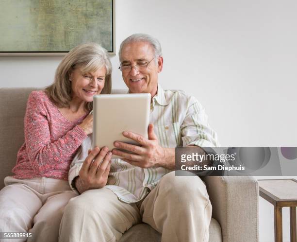 older caucasian couple using digital tablet on sofa - wellness kindness love stock pictures, royalty-free photos & images