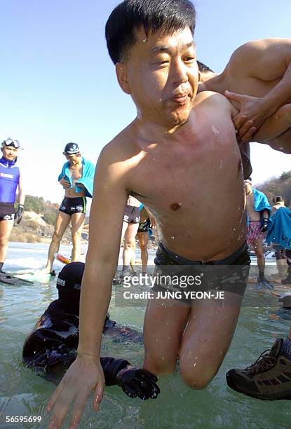 South Korean man swims out of iced water during an ice-diving contest through a hole of the frozen Hantan River in Cheorwon, some 90Km north of...