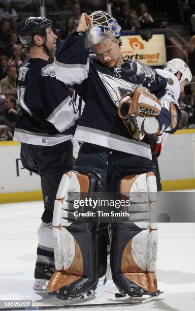 Goalie Jussi Markkanen of the Edmonton Oilers pulls off his mask to wipe ice off of his face as team-mate Jason Smith looks down the ice during the...