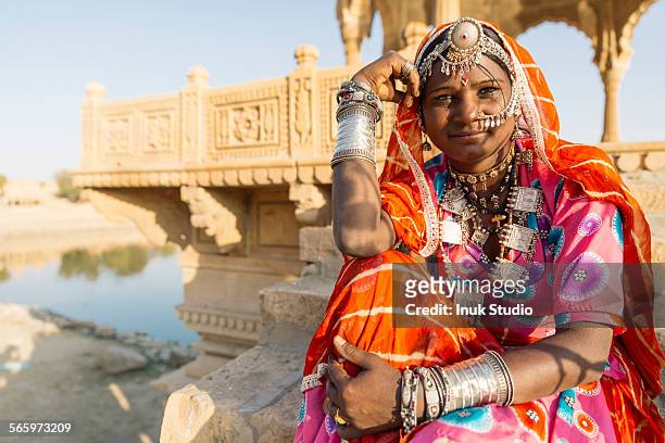 indian woman wearing traditional jewelry sitting near monument, jaisalmer, rajasthan, india - jaisalmer stock-fotos und bilder