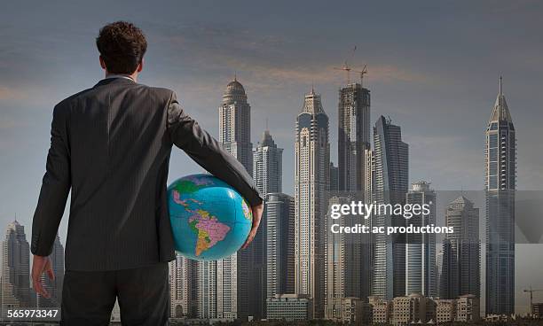 caucasian businessman holding globe near qatar cityscape, qatar - 1 earth productions stock pictures, royalty-free photos & images