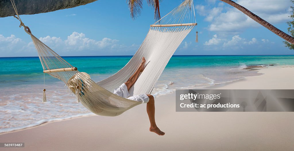 Caucasian woman laying in hammock on tropical beach