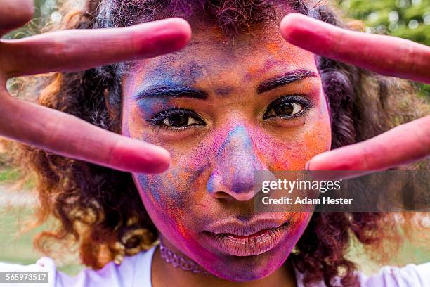 mixed race woman covered in pigment powder gesturing peace signs - color run stock-fotos und bilder