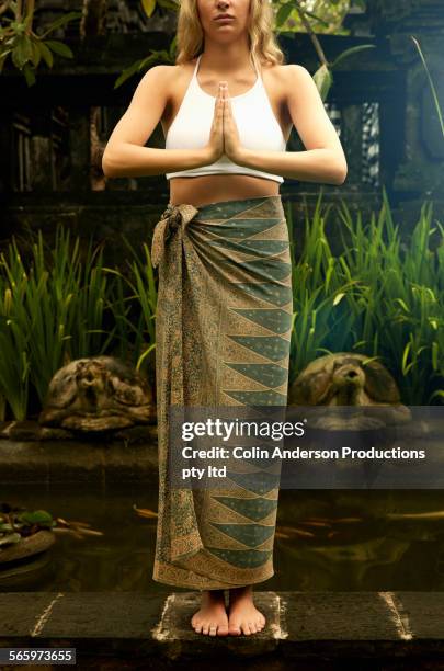 caucasian teenage girl meditating in garden - sarong stock pictures, royalty-free photos & images