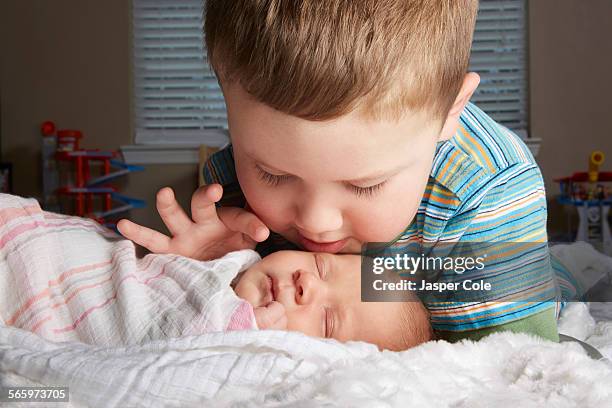 Boy admiring newborn sibling on bed