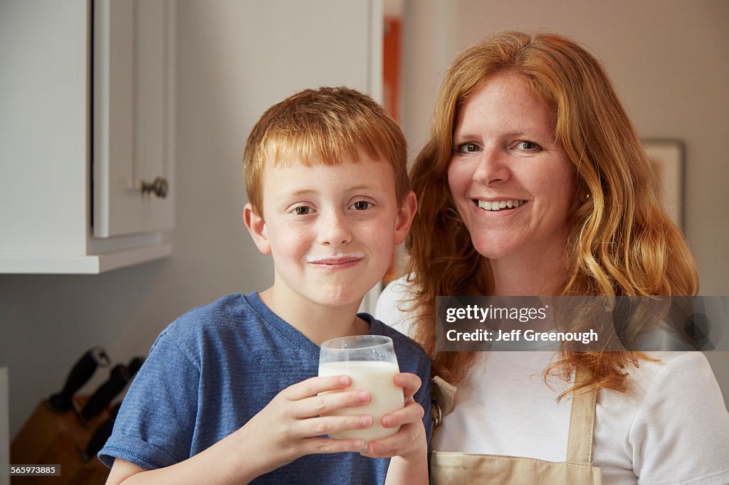 Caucasian mother and son drinking milk in kitchen