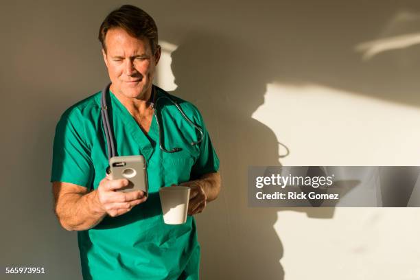 caucasian nurse using cell phone casting shadow on wall - 50 sombras fotografías e imágenes de stock