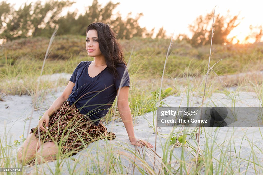 Hispanic woman sitting on sand dunes